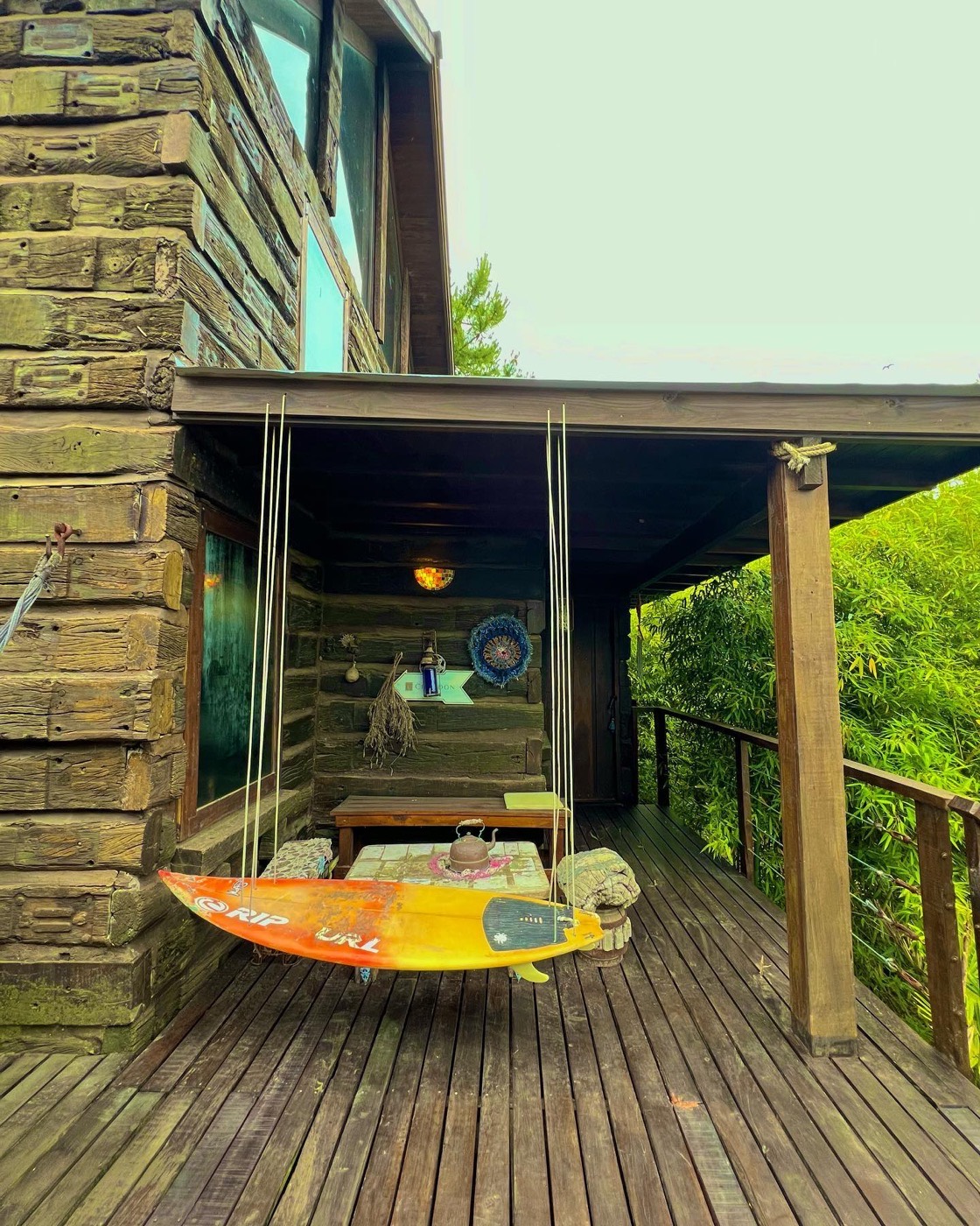 Galería con hamaca paraguaya y tabla de surf